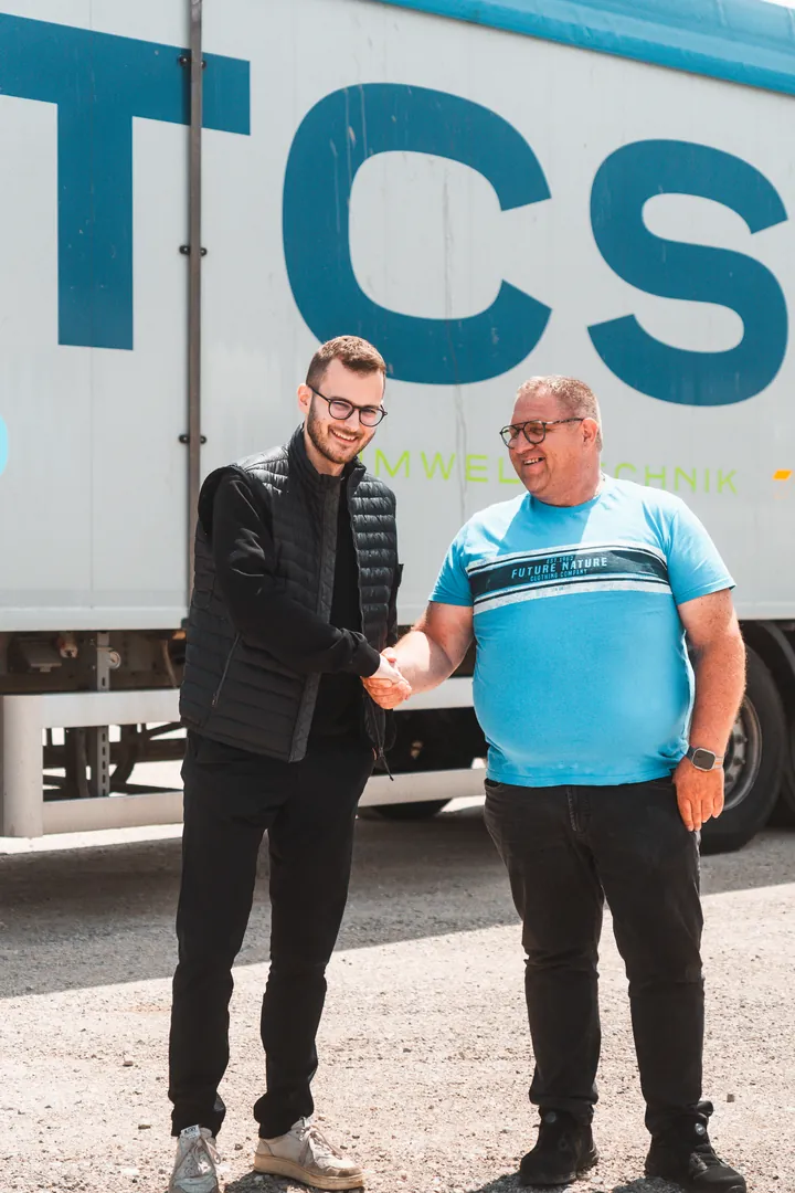 Handschlag zwischen einem Mitarbeiter von marketingwerk und einem Kunden vor einem LKW